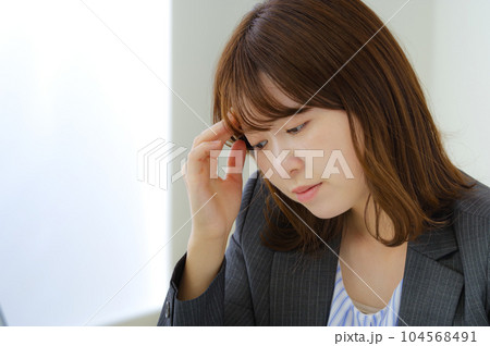疲労が溜まってつらそうな女性社員 疲労が溜まってつらそうな女性社員 104568491