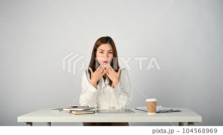 A surprised Asian businesswoman covering her mouth, feeling excited with unbelievable news A surprised Asian businesswoman covering her mouth, feeling excited with unbelievable news 104568969
