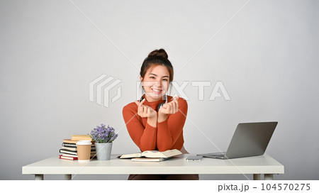 Young charming female college student sitting at her study desk. Young charming female college student sitting at her study desk. 104570275