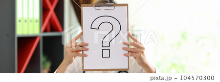 Woman practitioner covering face with paper with question mark 104570300