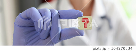 Female doctor hand in glove holding question mark sign Female doctor hand in glove holding question mark sign 104570334