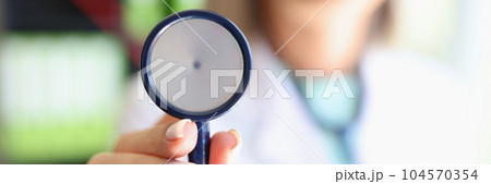 Woman doctor posing in clinic office and showing stethoscope 104570354