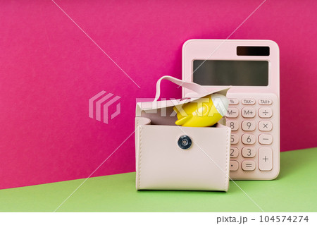 Yellow rocket on desk in pink briefcase with calculator on magenta background. copy space for back to school education and creativity concept. Cost of Success ideas. STEM or small business 104574274