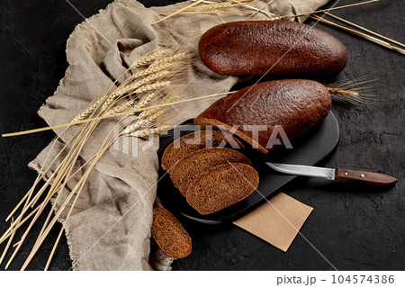 Whole and sliced rye bread with ears of wheat and burlap Whole and sliced rye bread with ears of wheat and burlap 104574386