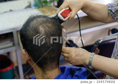 Close-up of hairdresser using electric hair clipper for cut human head hair in barber shop. Conceptual of Barber serving hair cut service to customer. Close-up of hairdresser using electric hair clipper for cut human head hair in barber shop. Conceptual of Barber serving hair cut service to customer. 104574608