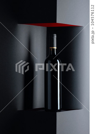 Unopened bottle of red wine on a black background. Copy space. 104576112