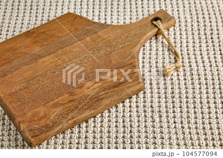 Wooden brown cutting board on the background of a knitted beige plaid Wooden brown cutting board on the background of a knitted beige plaid 104577094