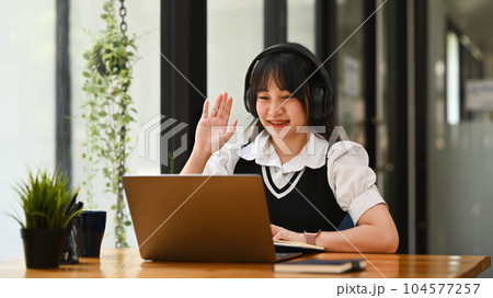 Smiling asian female student wearing headphones learning online, watching webinar class on laptop 104577257