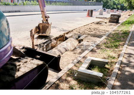 Big jackhammer drill drilling road.Heavy machinery crushing asphalt for stormwater drain repair. excavator tracks in the water. repair and expansion of a road Big jackhammer drill drilling road.Heavy machinery crushing asphalt for stormwater drain repair. excavator tracks in the water. repair and expansion of a road 104577261