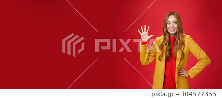 Girl giving five stars to awesome internet store she bought outfit for autumn weather showing raised palm smiling broadly as standing in stylish warm yellow coat over red background 104577355