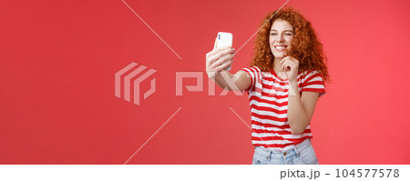 Sassy good-looking stylish charismatic redhead female curly hairstyle winking cheeky expression making flirty kinky faces hold smartphone taking selfie record video message play funny facial filters 104577578