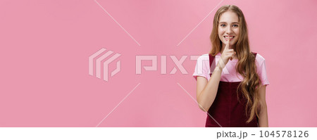 Girl wanna share her beauty secret smiling tricky and friendly showing shush gesture with index finger over mouth to save surprise and mystery posing delighted and relaxed over pink background Girl wanna share her beauty secret smiling tricky and friendly showing shush gesture with index finger over mouth to save surprise and mystery posing delighted and relaxed over pink background 104578126