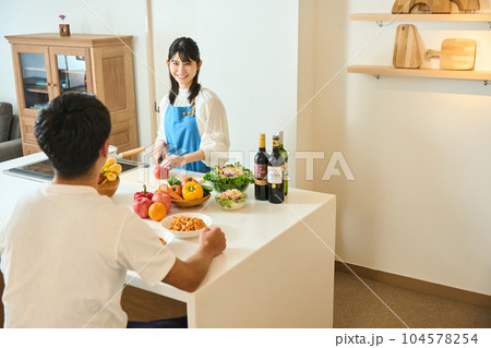 カウンターキッチンで料理をする男女 カウンターキッチンで料理をする男女 104578254