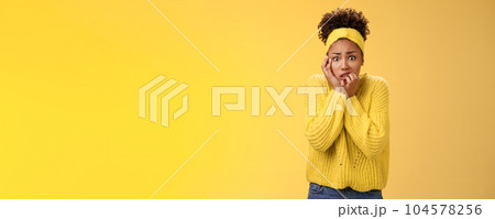 Afraid concerned nervous young african american female employee worried anxious be fired clench teeth stooping touch face insecure bit fingers standing scared terrified, yellow background 104578256