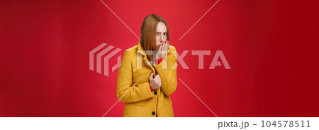 Girl getting cold, coughing and buttoning yelling light coat as freezing on chilly, windy weather looking displeased and ill at camera, feeling unwell catching flu over red background 104578511