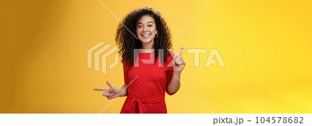Charismatic cute and happy young curly-haired european female in red dress dancing and pointing up and right, showing sideways as presenting choices picking, making decision and smiling at camera Charismatic cute and happy young curly-haired european female in red dress dancing and pointing up and right, showing sideways as presenting choices picking, making decision and smiling at camera 104578682