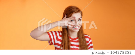 Charismatic lovely redhead lucky female, smiling cute, peek camera tender coquettish gaze, hold palm face, look through fingers, stand orange background optimistic, cheerful mood Charismatic lovely redhead lucky female, smiling cute, peek camera tender coquettish gaze, hold palm face, look through fingers, stand orange background optimistic, cheerful mood 104578855