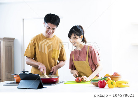 タブレットを見ながら料理をする若い夫婦 タブレットを見ながら料理をする若い夫婦 104579023