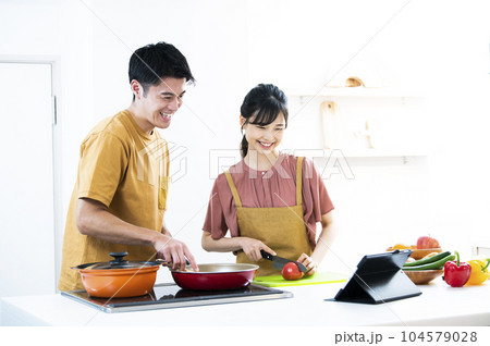 タブレットを見ながら料理をする若い夫婦 104579028