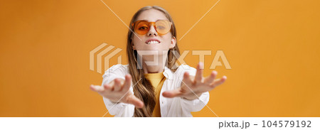 Girl reaching with desire at camera wanting grab it. Portrait of good-looking stylish caucasian young woman in trendy sunglasses biting lip from will to have something pulling hands towards 104579192