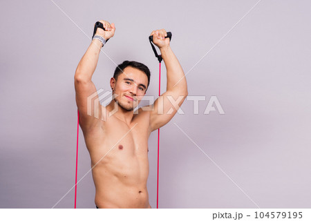 Fit young athlete preparing for bicep muscle arms exercise. Isolated over grey studio background. 104579195