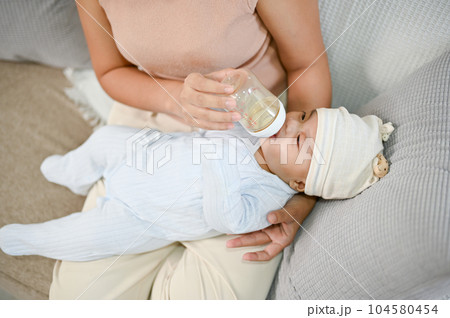 Portrait of cute newborn baby being fed by her mother using bottle. motherhood 104580454