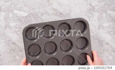 Flat lay. Step by step. Lining cupcake baking pan with foil cupcake liners to bake unicorn rainbow chocolate cupcakes. 104581704