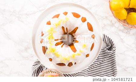 Flat lay. Step by step. Garnishing lemon bundt cake with lemon zest on top of the white glaze. 104581721