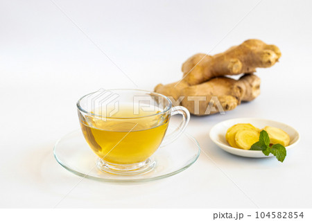 a cup of tea with ginger root, lime, cinnamon and teapot on white background. Health drink concept.. 104582854