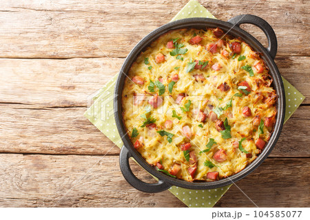Dibbelabbes German casserole is a traditional country oven dish with potatoes, leeks, onions and bacon close-up in a pan. Horizontal top view 104585077