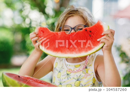Little Girl, Preschooler, Delights in a Juicy Watermelon on a Sunny Summer Day. Child sharing a Healthy Snack with Her Family, She Embraces the Joy of Summertime Bliss Little Girl, Preschooler, Delights in a Juicy Watermelon on a Sunny Summer Day. Child sharing a Healthy Snack with Her Family, She Embraces the Joy of Summertime Bliss 104587260