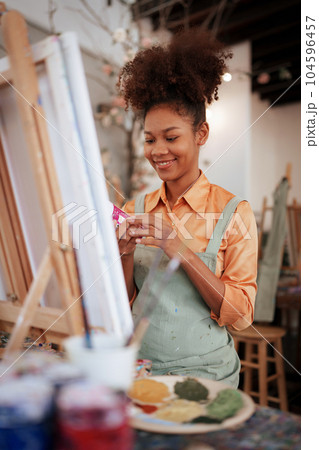Beautiful American African artist woman painting in art studio at the university classroom Beautiful American African artist woman painting in art studio at the university classroom 104596457