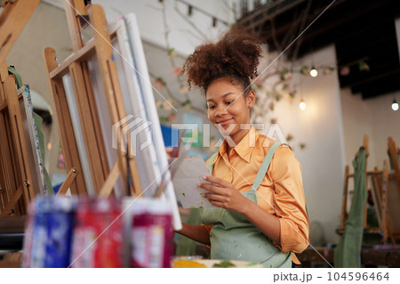 Beautiful American African artist woman painting in art studio at the university classroom 104596464