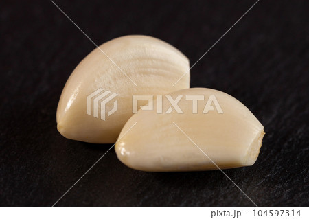 Garlic cloves. Raw garlic isolated on black background. Vegetable 104597314