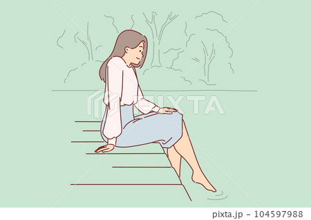 Woman is sitting on pier, lowering into water and enjoying silence and good summer weather Woman is sitting on pier, lowering into water and enjoying silence and good summer weather 104597988