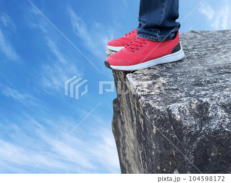 崖っぷちに立つスニーカーを履いた男性の足元 崖っぷちに立つスニーカーを履いた男性の足元 104598172