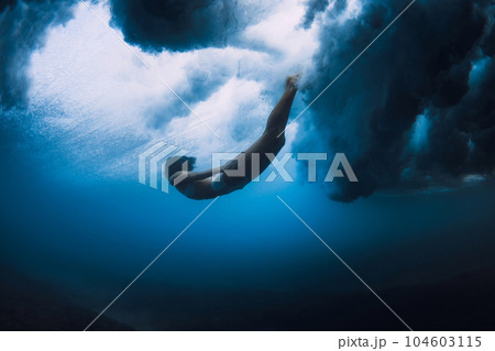 Surfer girl dive underwater with ocean powerful and dangerous wave. Surfer girl dive underwater with ocean powerful and dangerous wave. 104603115