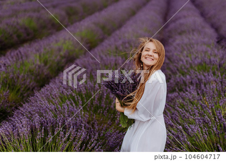 Happy Woman with Bouquet in Blooming Lavender Field 104604717