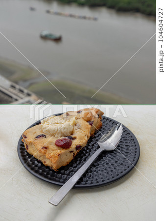 Homemade Vanilla Mixed Cream Cheese Granberry Scone served with spoon on black ceramic plate. 104604727