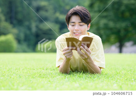 芝生にうつ伏せで読書する男性 芝生にうつ伏せで読書する男性 104606715