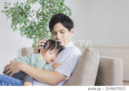 子供を抱っこして寝かしつける父親 104607025