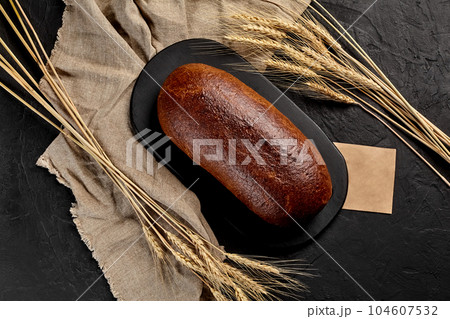 Whole rye bread with ears of wheat, burlap and piece of craft paper 104607532