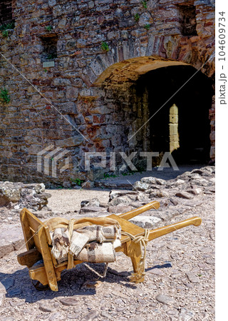 Old-fashioned wheelbarrow - Raglan Castle, Monmouthshire, South Wales Old-fashioned wheelbarrow - Raglan Castle, Monmouthshire, South Wales 104609734