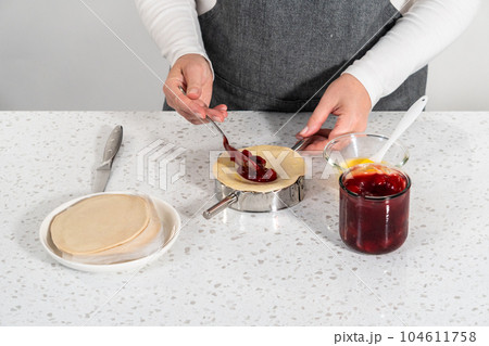 Filling empanada dough with cherry pie filling to make sweet cherry empanadas in the air fryer. Filling empanada dough with cherry pie filling to make sweet cherry empanadas in the air fryer. 104611758