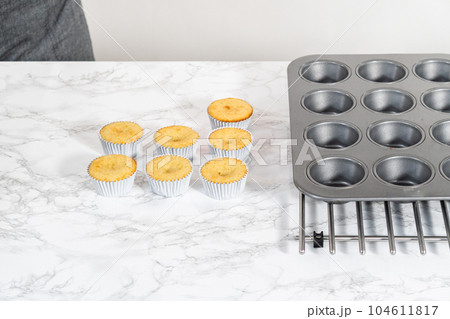 Cooling freshly baked lemon cupcakes on a kitchen counter. 104611817