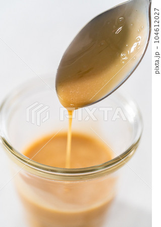 Spooning eggnog caramel sauce from the glass jar. Spooning eggnog caramel sauce from the glass jar. 104612027
