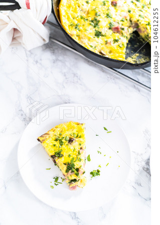 Slice of spinach and ham frittata on a white dinner plate. Slice of spinach and ham frittata on a white dinner plate. 104612255