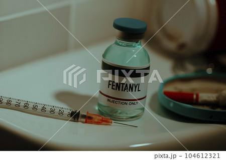 vial of fentanyl and syringe on a toilet 104612321