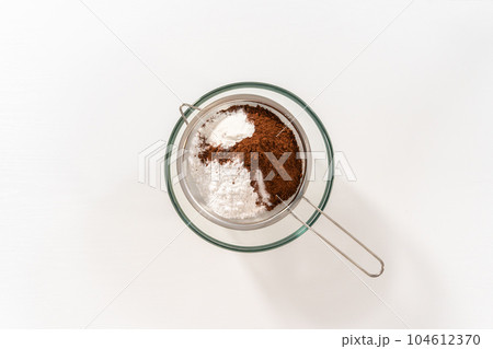 Flat lay. Sifting ingredients through hand sifter to make homemade hot chocolate mix. Flat lay. Sifting ingredients through hand sifter to make homemade hot chocolate mix. 104612370