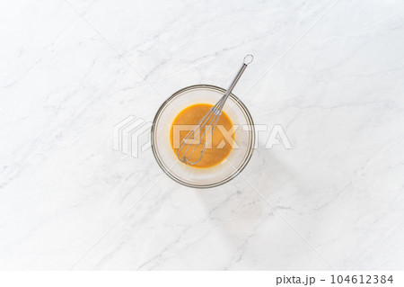 Flat lay. Mixing ingredients with a hand mixer in a small mixing bowl to make the eggnog caramel sauce. Flat lay. Mixing ingredients with a hand mixer in a small mixing bowl to make the eggnog caramel sauce. 104612384